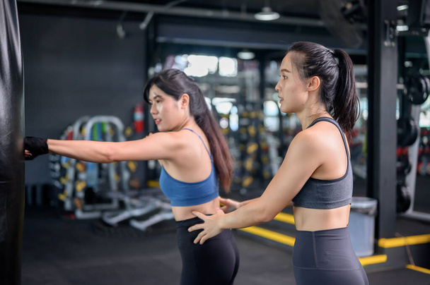 Asian woman exercise and lifestyle at fitness gym. Sporty woman workout and boxing with trainer. Wellness and healthy for bodybuilding. - Foto, afbeelding