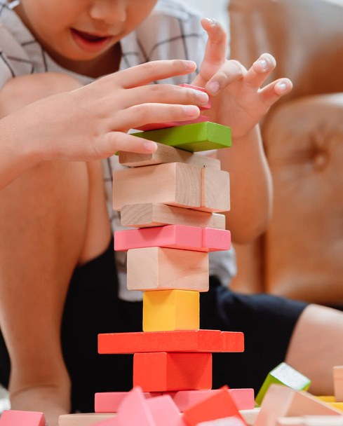 Asijská matka pracuje doma se synem. Máma a děcko si hrají na barevný dřevěný blok. Dítě vytváří stavební hračku. Ženské životní styl a rodinná aktivita. - Fotografie, Obrázek