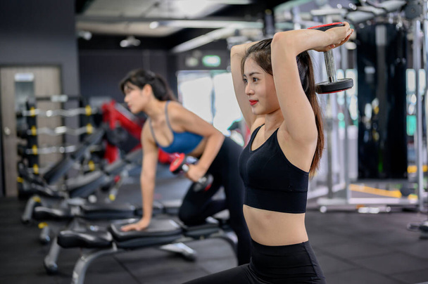 Spor salonunda Asyalı kadın egzersizi ve yaşam tarzı. Spor kadın antrenörü ve dambıl ağırlığında. Vücut geliştirmek için sağlıklı ve sağlıklı.. - Fotoğraf, Görsel