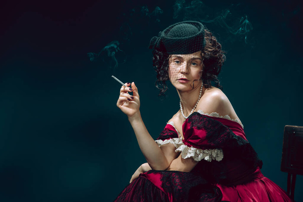 Young woman as Anna Karenina on dark blue background. Retro style, comparison of eras concept. - 写真・画像