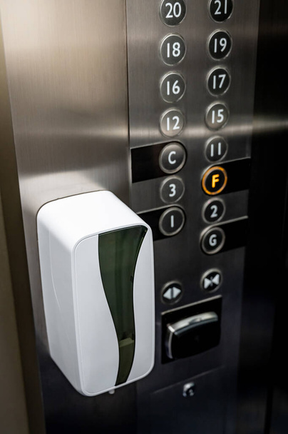 Distributore automatico di alcol per la pulizia manuale in ascensore o ascensore. Concetto di prevenzione delle infezioni da Coronavirus (COVID-19). Sicuro e pulito nell'edificio pubblico. - Foto, immagini