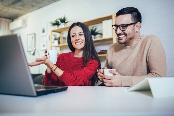 Ευτυχισμένο ζευγάρι κάνει επιχειρήσεις μαζί εργάζονται στο σπίτι για το φορητό υπολογιστή. - Φωτογραφία, εικόνα