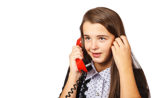 teenage brunette smiling girl talking on red retro telephone closeup on white background - Fotó, kép