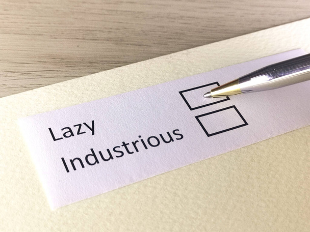 One person is answering question on a piece of paper. The person is thinking to be lazy or to be industrious. - Photo, Image