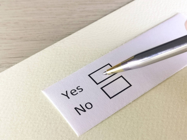 Une personne répond à une question sur un bout de papier. La personne pense à choisir oui ou non. - Photo, image