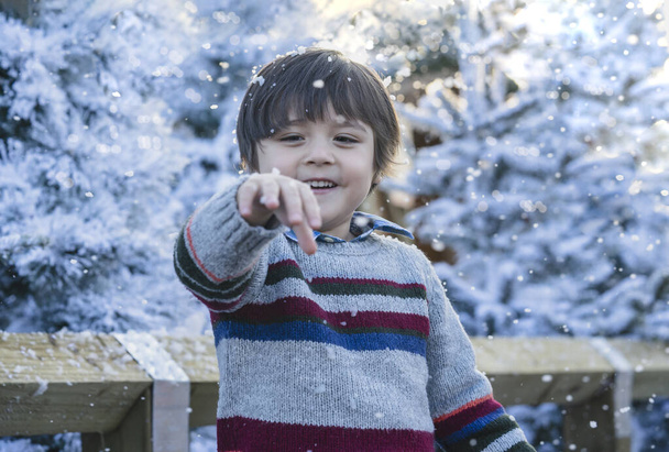 Criança feliz com rosto sorridente brincando com bolhas de espuma com fundo de luz bokeh embaçado, menino bonito jogando ao ar livre na feira de inverno, criança se divertindo atividade ao ar livre no dia nevado no mercado de Natal - Foto, Imagem