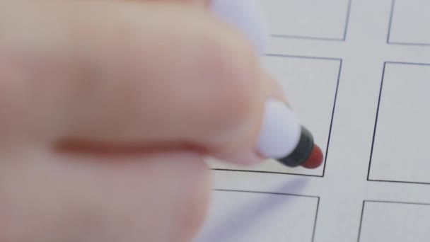La mano femenina dibuja una cruz roja en la casilla de verificación del voto. Concepto de elección y decisión - Metraje, vídeo