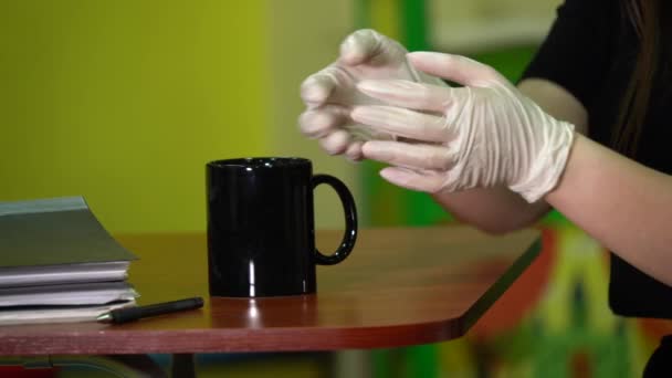 Frau trinkt aus einer schwarzen Tasse in Latex-Handschuhen. - Filmmaterial, Video
