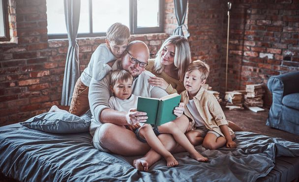 Glückliche Jungen und ihre Eltern lesen Märchen im Hotel - Foto, Bild