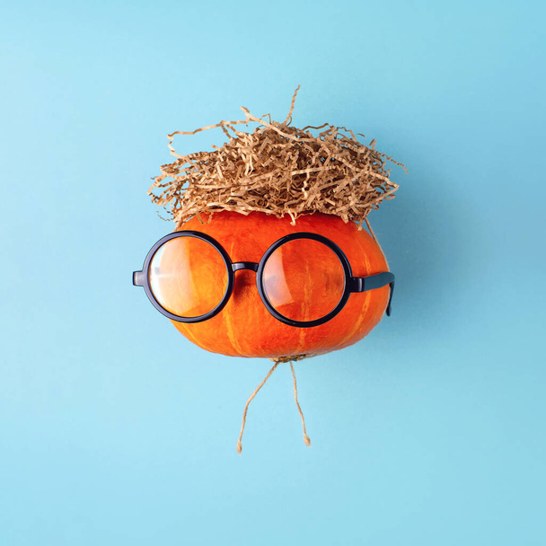 Orange pumpkin in glasses and with a hair of hay. Halloween concept. - Foto, Imagen