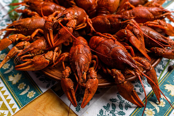 boiled crayfish on a plate on a blue tablecloth on a wooden table - Foto, Bild