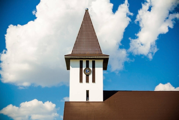La partie supérieure de la structure de l'Eglise catholique, sur fond de ciel bleu d'été, avec des nuages. - Photo, image
