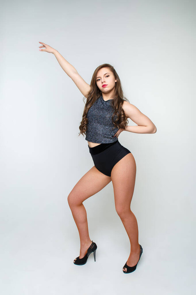 Sexy young woman with long hair in black shorts red tights on a light background in full growth. - Foto, afbeelding