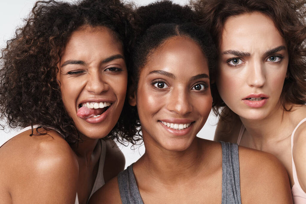 Portrait of gorgeous multiracial women standing together and looking at camera isolated over white background - Fotografie, Obrázek