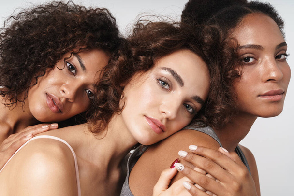 Portrait of three attractive multiethnic women hugging together isolated over white background - Фото, зображення