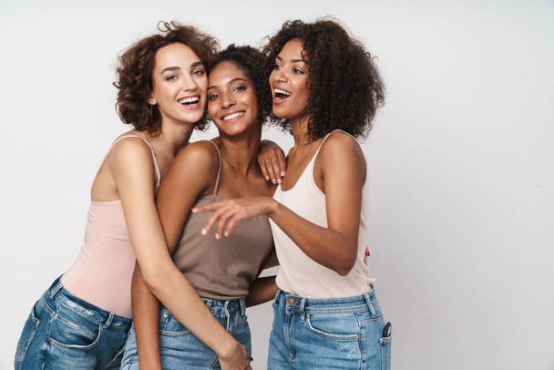 Portrait of three joyful multiethnic women standing and laughing together isolated over white background - Zdjęcie, obraz