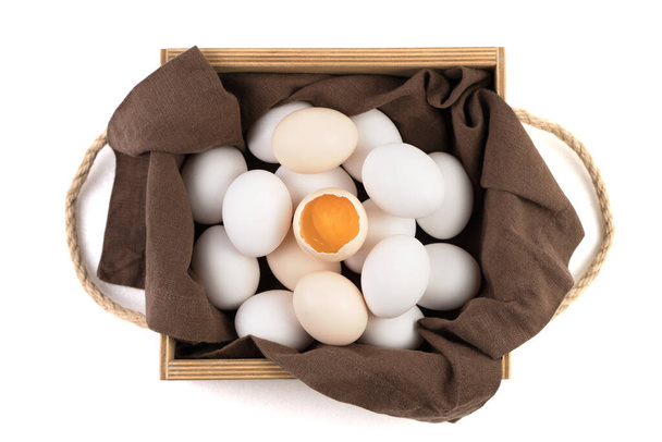 鶏の卵は白と茶色で、中央に割れた卵があり、そこには新鮮な黄身が見える。. - 写真・画像