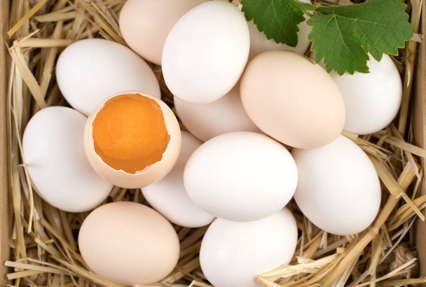 Œufs de poulet blancs et bruns avec un œuf cassé au centre. - Photo, image