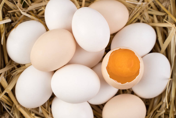 Ovos de galinha de cor branca e marrom com um ovo quebrado no centro. - Foto, Imagem