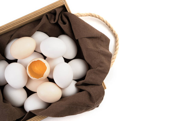 Yumurtalar beyaz ve kahverengidir. Ortasında kırık bir yumurta vardır. Taze yumurta sarısı görülebilir.. - Fotoğraf, Görsel