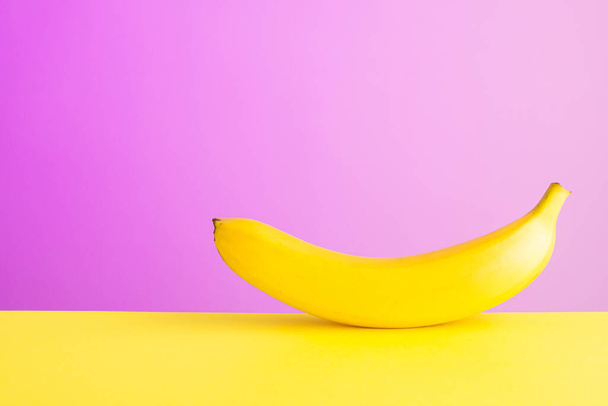 dojrzały banan na żółtym tle tabeli fioletowy, kontrast kolorów - Zdjęcie, obraz