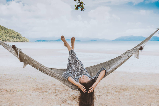 Nainen rentouttava riippumatossa jalat ylös trooppisella rannalla kesälomalla - Valokuva, kuva