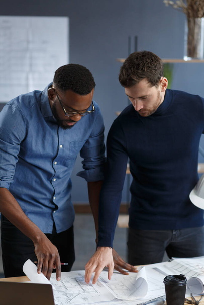 Multiracial engineer team working in office with blue prints and architect equipment sketching,discussing and planning construction project. Partners disputing at work. Business construction concept - Foto, imagen