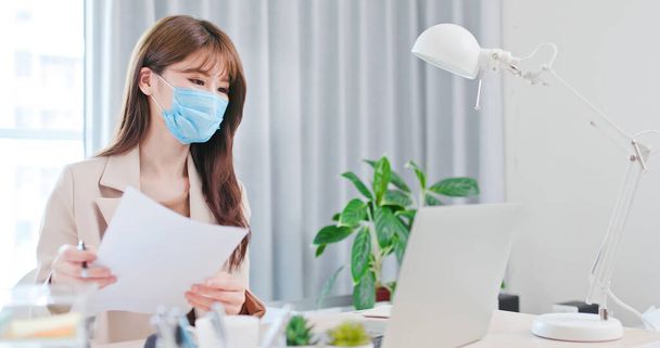 telework concept - Asian business woman wear face mask is self quarantine and she use computer to join a video meeting at home - Zdjęcie, obraz