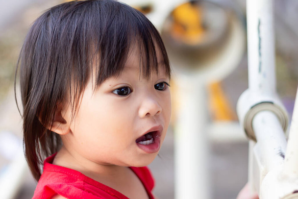 Portrét dítěte ve věku 1 až 2 let. Šťastné asijské dítě dívka usmívá a dívá se do kamery na hřišti. Face emotions of kid concept. - Fotografie, Obrázek