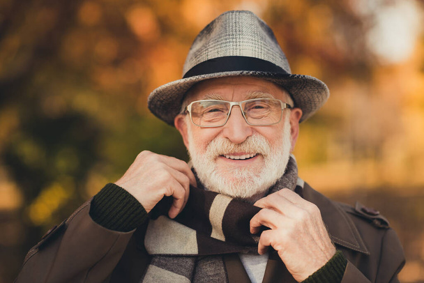 Closeup photo of cheerful glad retired old grey haired grandpa central park walk enjoy sunny day weather toothy smiling wear stylish autumn jacket hat scarf specs colorful street outside - Fotografie, Obrázek