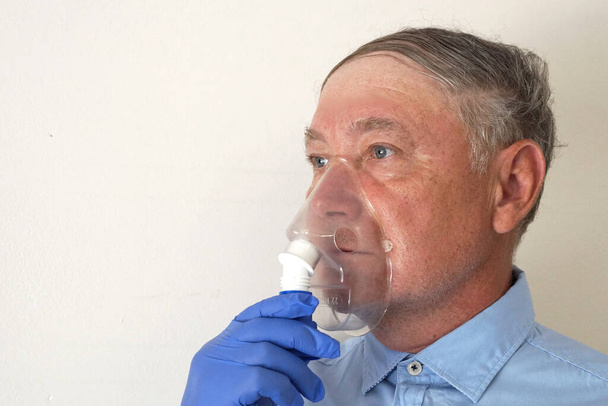 alter Mann atmet durch einen Inhalator, Porträt aus nächster Nähe - Foto, Bild