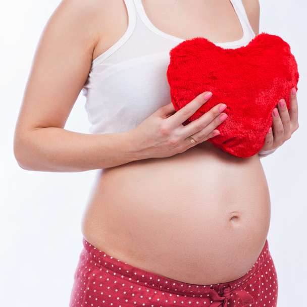 Pregnant mother showing her belly and holding a toy - Photo, Image