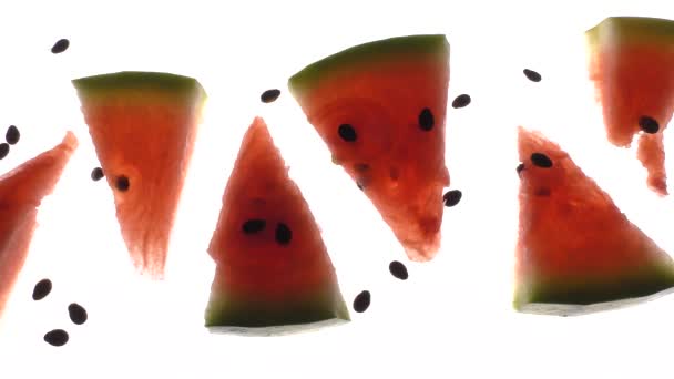 Sliced juicy watermelon on a backlight and on a white background in camera movement. - Footage, Video