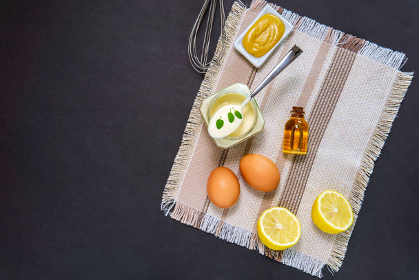 domowej roboty biały sos majonez i składniki jajka, oliwa z oliwek cytryny na czarnym tle. Widok z góry - Zdjęcie, obraz