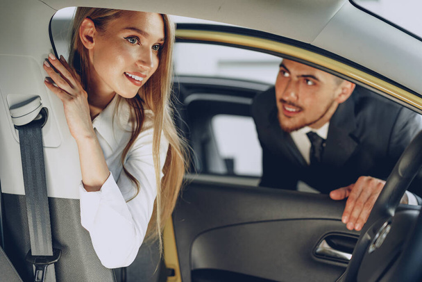 Man car dealer showing a woman buyer a new car - Foto, immagini