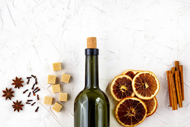 Bottle of wine and spice on white background. Ingredients for a mulled wine. Cinnamon, anise stars, orange, brown sugar, cloves. Christmas hot drink - 写真・画像