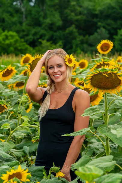 Un magnifique modèle blond pose à l'extérieur dans un champ de tournesols tout en profitant d'une journée d'été - Photo, image