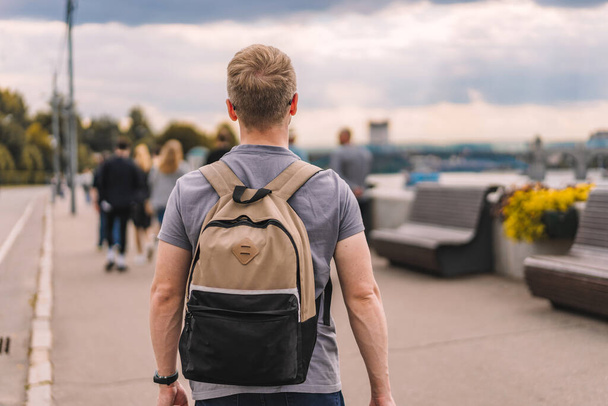 Un jeune homme avec un sac à dos se promène dans un parc public en été, photo de dos - Photo, image