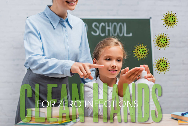 teacher pointing with finger at sanitizer near schoolgirl and clean hands for zero infections lettering in classroom  - Photo, Image