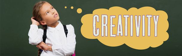 панорамный снимок вдумчивой школьницы, трогающей голову и смотрящей на доску с креативным надписью  - Фото, изображение