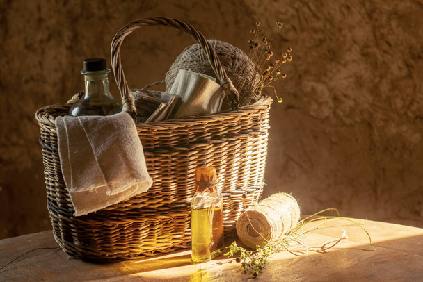 Flax products. Linen cloth, flaxseed oil, threads in balls and dry flax plants in a basket. Retro style - Фото, зображення