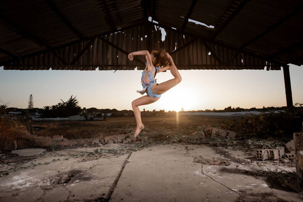 Молода дівчина виконує ритмічні гімнастичні вправи на відкритому повітрі
 - Фото, зображення