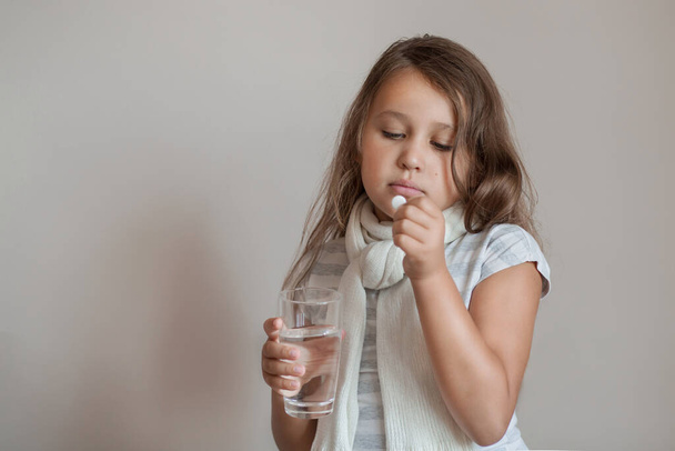 Litlle lány influenzás, fehér pohár víz és tabletta - Fotó, kép