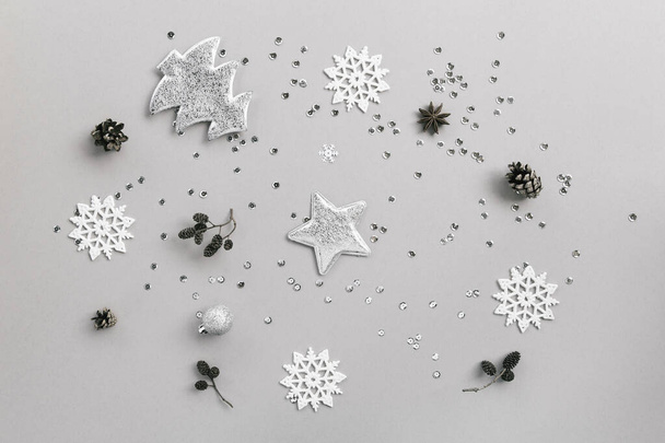 Творческая зимняя композиция с сосновыми шишками, декоративной серебряной звездой, елкой, шарами и снежинками на пастельном фоне с блестками. Вид сверху. Плоский лежал - Фото, изображение