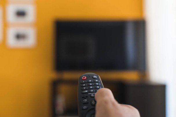 Hand holding remote control for watching tv in the living room - Photo, Image