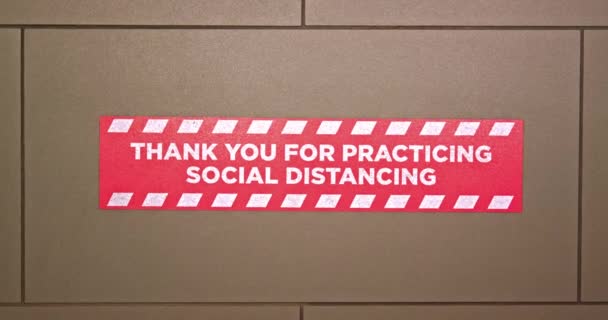 Red floor sign reminds travelers to practicing social distancing in hotel lobby - Footage, Video