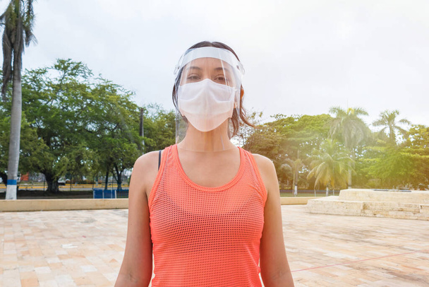 Mladá žena nosí ochrannou masku obličeje ve městě během COVID-19 - Fotografie, Obrázek