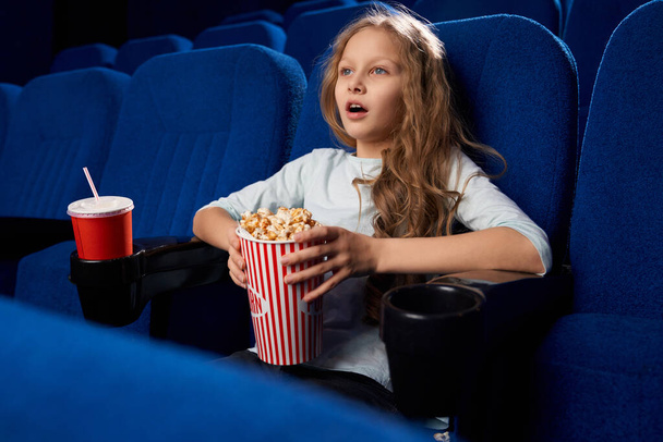 Little exited girl watching movie in cinema. - Foto, Imagen