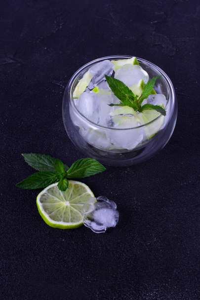 Mojito cooling set: ice cubes, lime and mint on a black background - Photo, Image