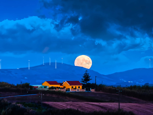 Paisaje con el amanecer de luna llena saliendo de las colinas por la noche - Foto, imagen